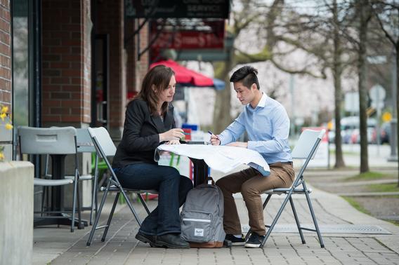 A teen and a researcher sitting together at an outdoor table..